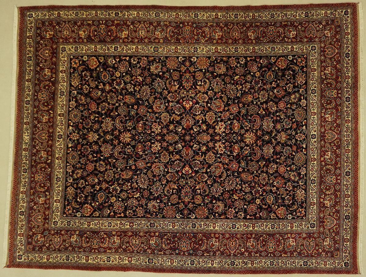 Rectangular Persian rug with floral pattern in dark blue, red, and gold, framed by detailed borders.