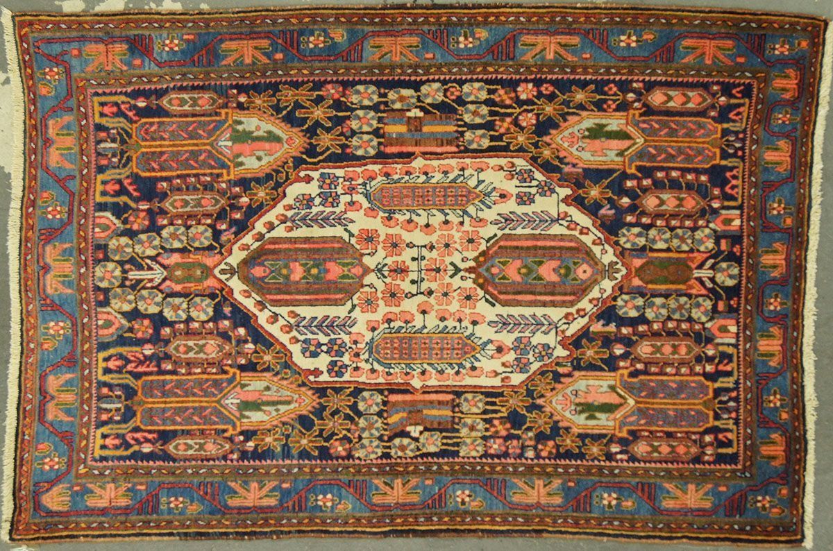 Oriental rug, navy blue field with a central white and red medallion, intricate floral border.