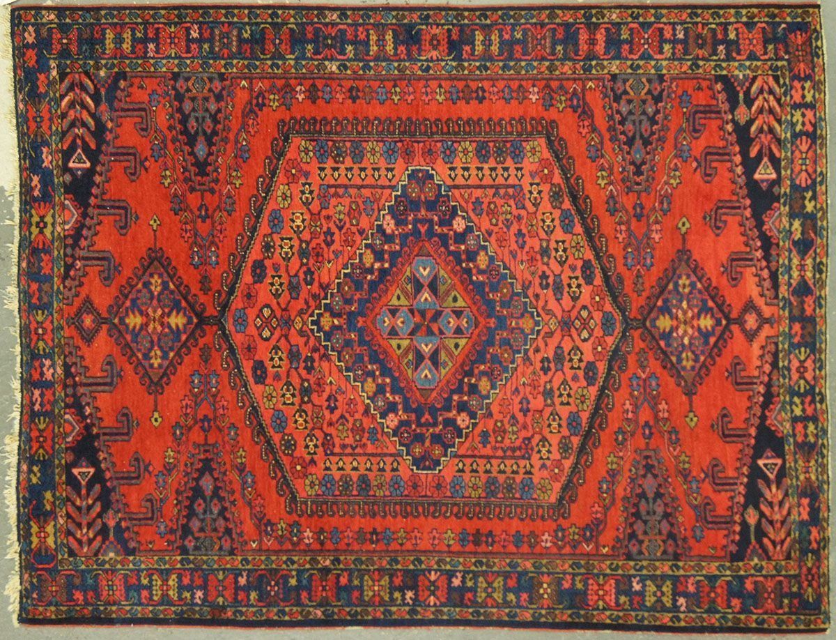 Red and navy oriental rug with a central hexagonal medallion and diamond accents.