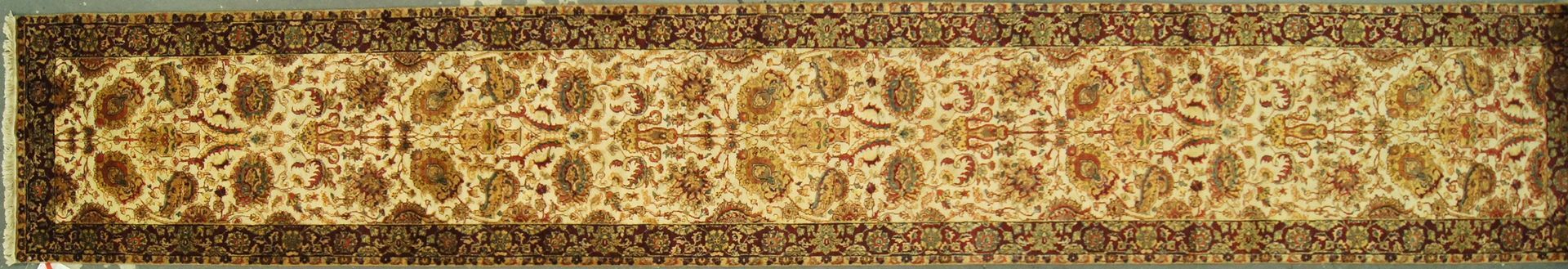 A rectangular rug with an intricate beige design bordered by dark brown.
