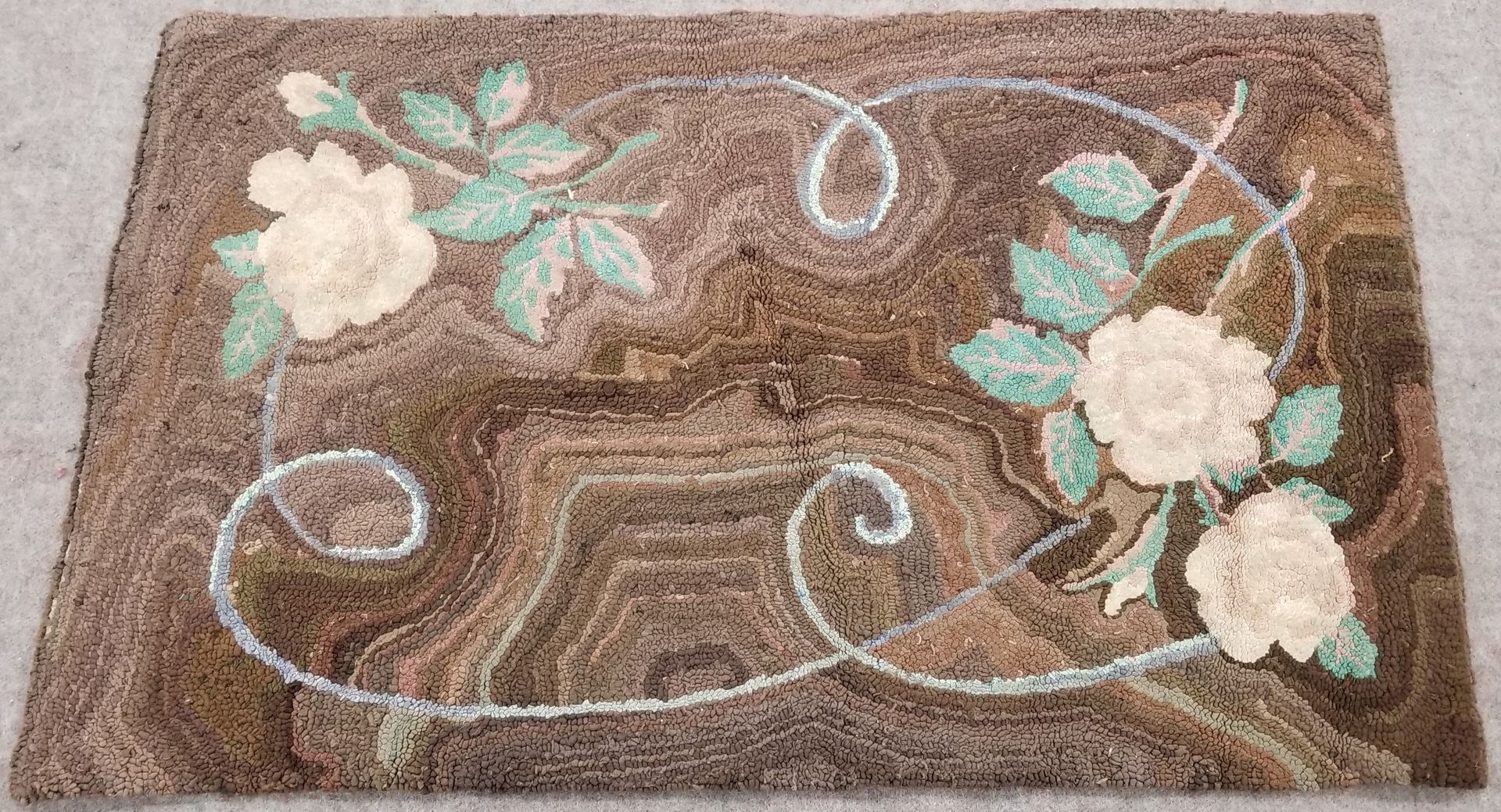 Brown rug with cream roses, teal leaves, and white swirls.