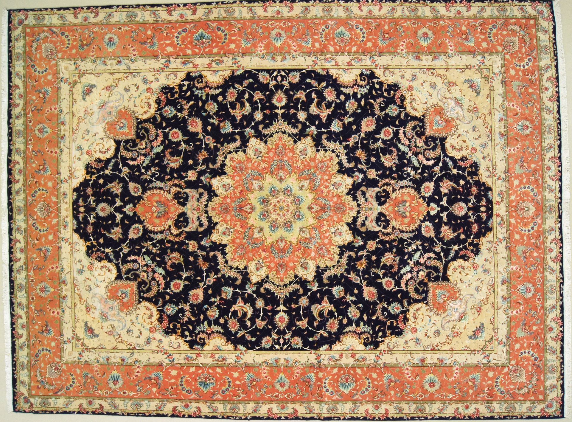 Oriental rug with a navy blue central medallion, cream background, and orange border.
