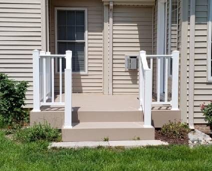 The front porch of a house with stairs and a white railing.