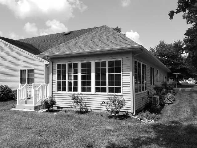 A black and white photo of a house with lots of windows.