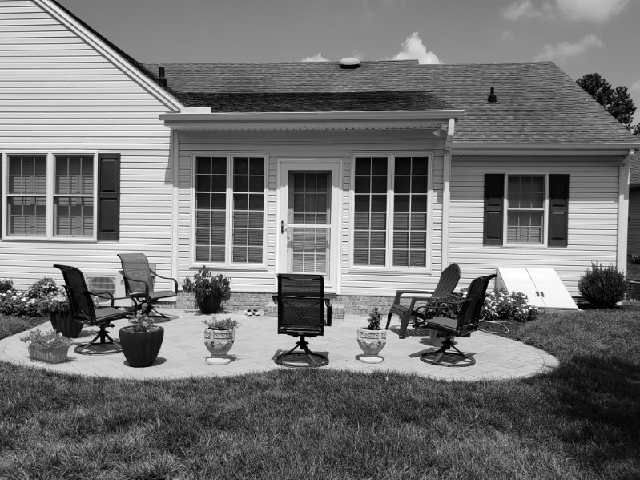 A black and white photo of a house with a patio in front of it