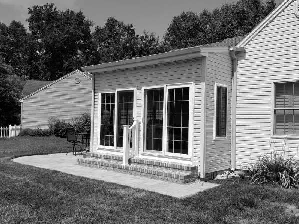 A black and white photo of a house with a sunroom.