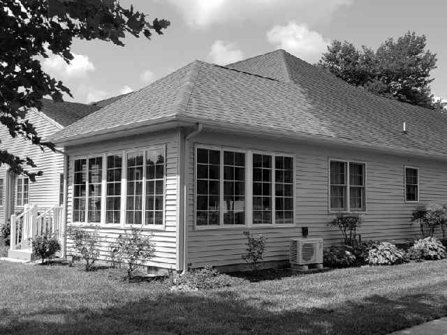 A black and white photo of a house with lots of windows