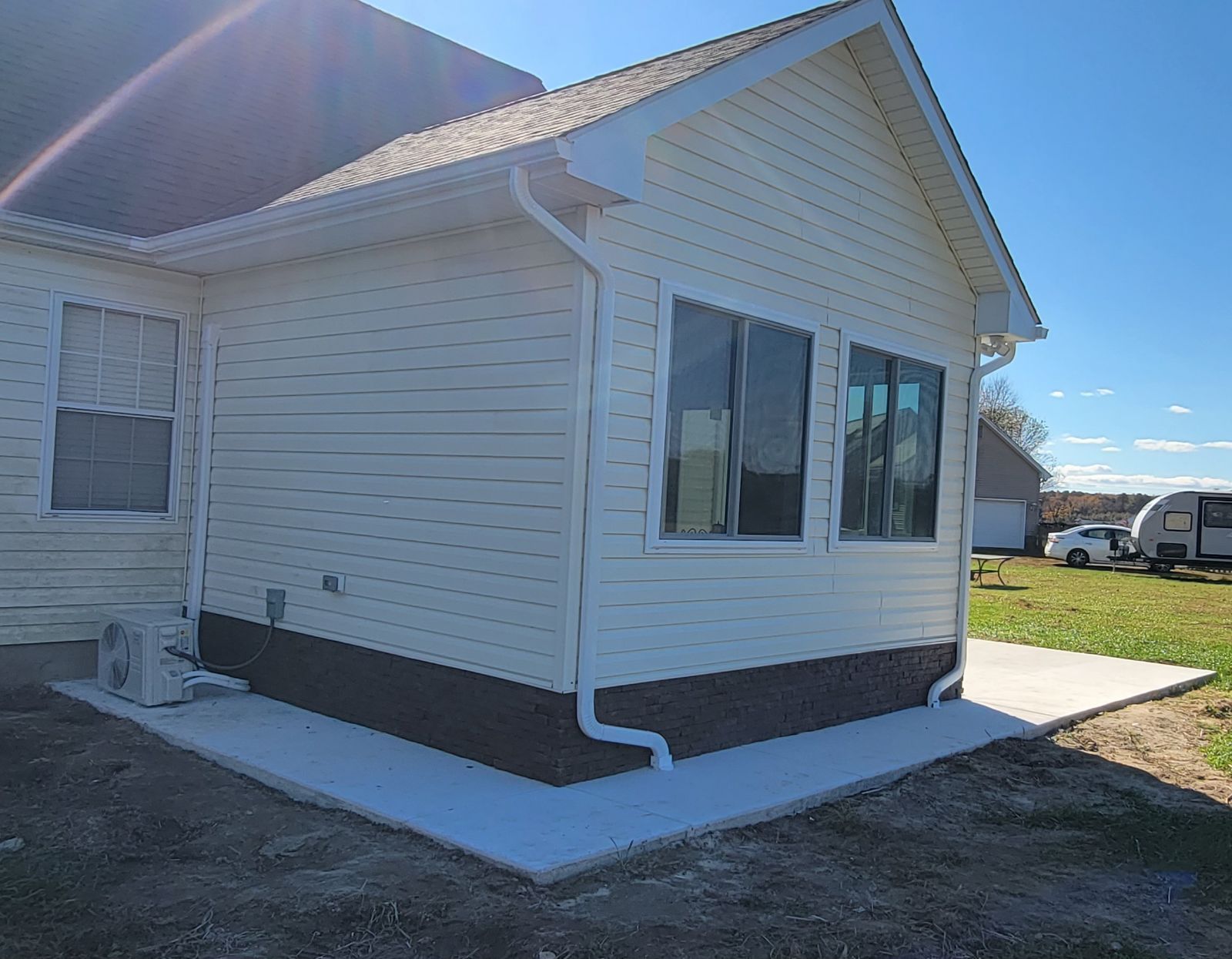 A white house with a lot of windows and a concrete walkway in front of it.