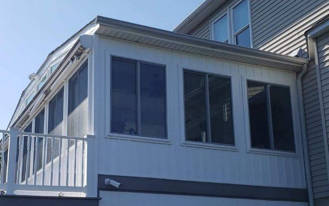 There is a screened in porch on the side of a house.