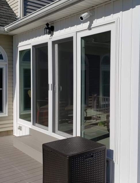 A white house with sliding glass doors and a wicker box on the deck.