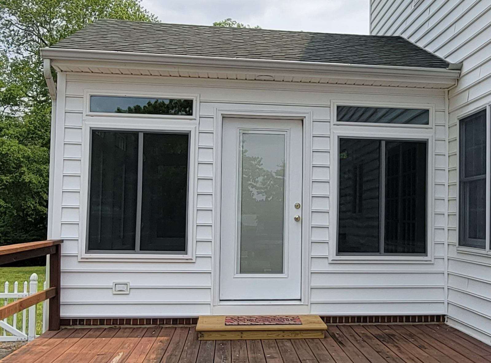 A white house with a screened in porch and a door.
