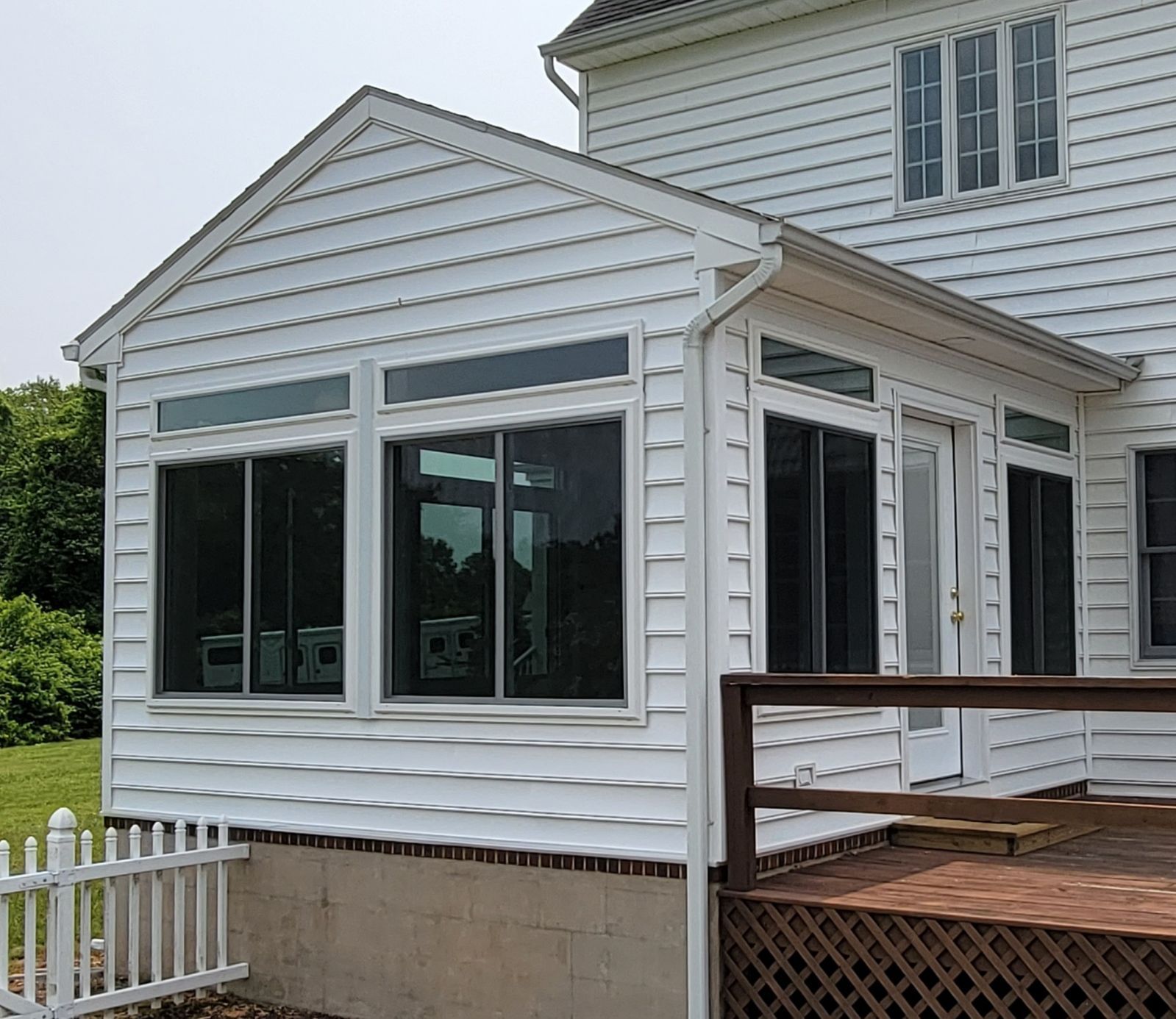 A white house with a screened in porch and a wooden deck