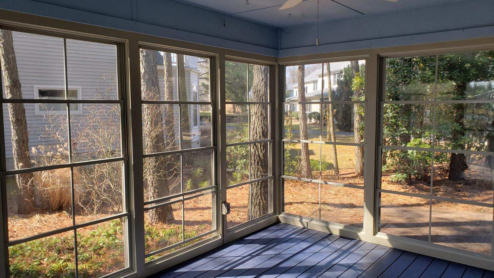 A screened in porch with a lot of windows and a ceiling fan.