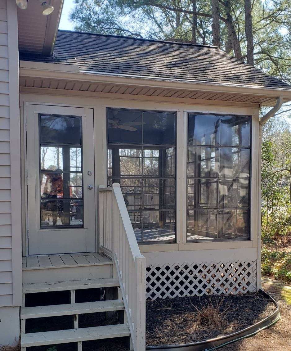 A white house with a screened in porch and stairs.