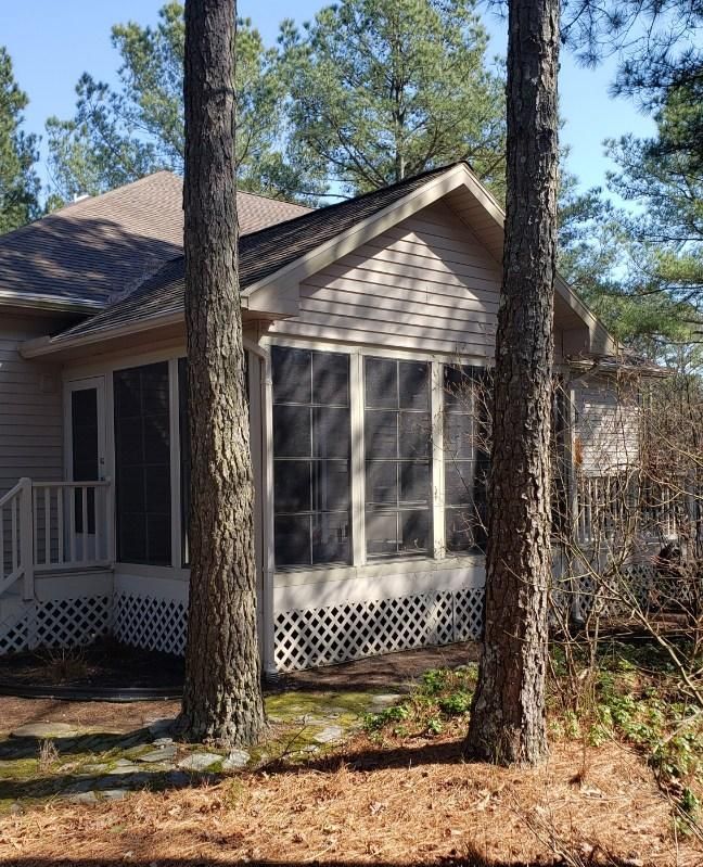 A house with a screened in porch surrounded by trees