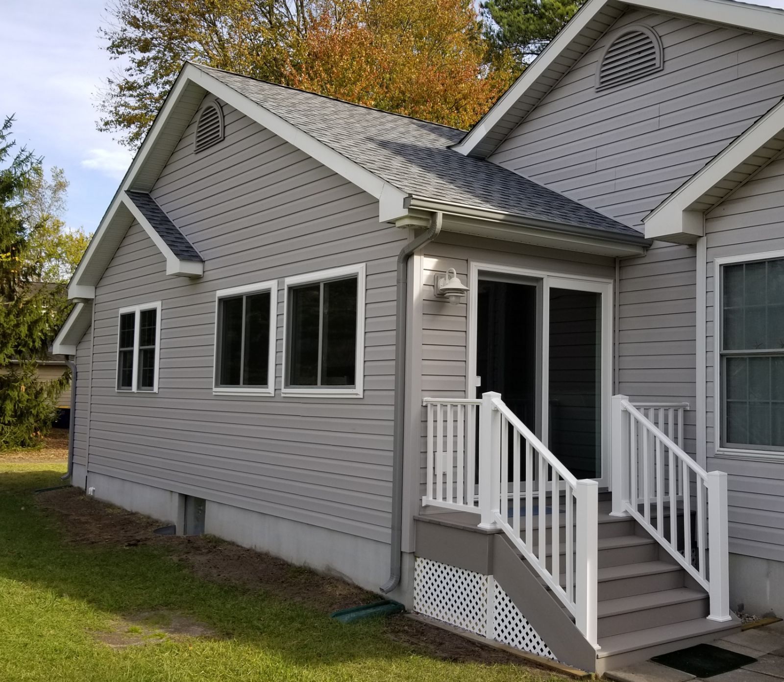 A gray house with a white railing and stairs