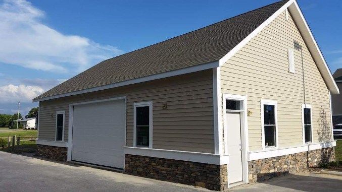 A large garage with a white door and a brown roof.