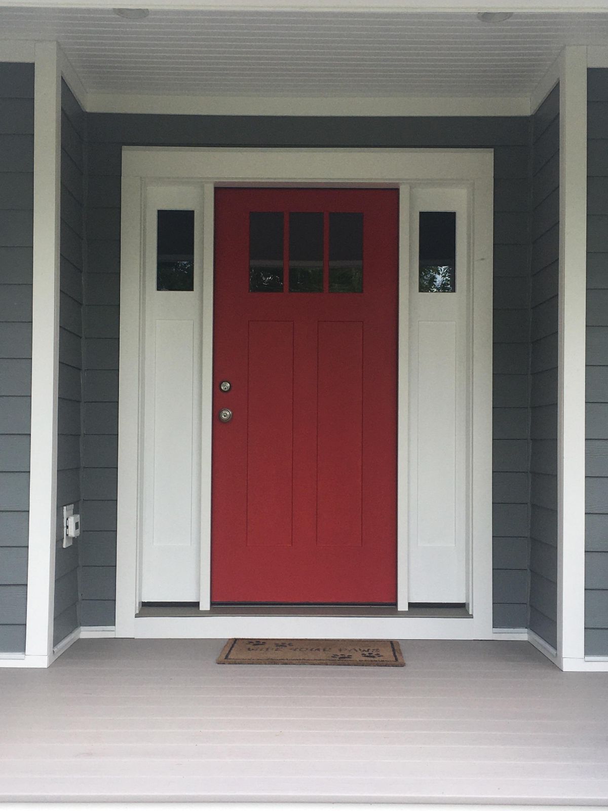 The front door of a house has a red door and white trim