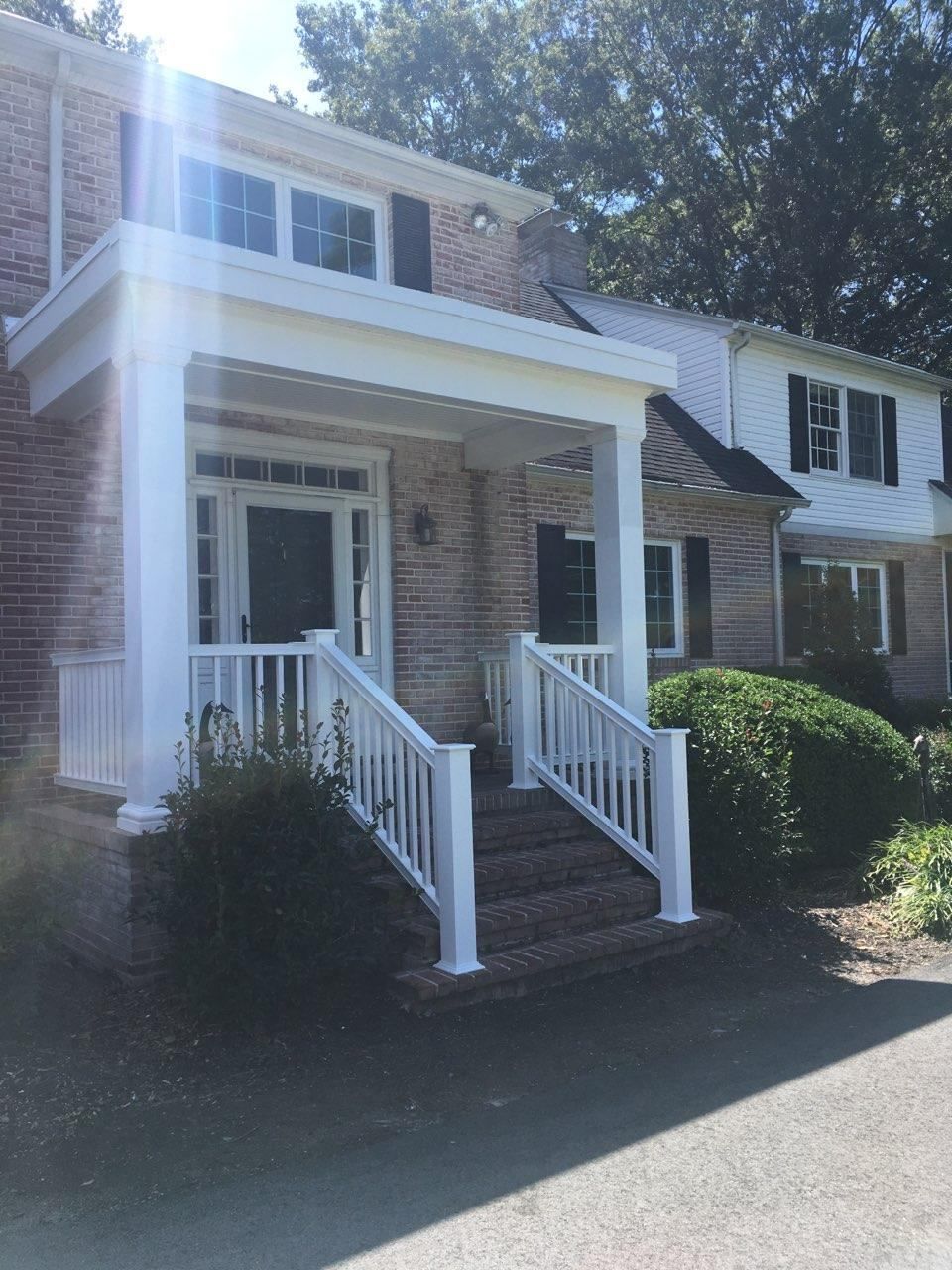 A brick house with a white porch and stairs