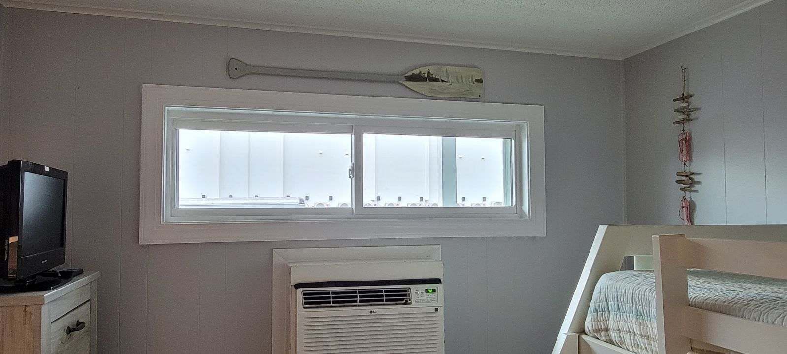 A bedroom with bunk beds, a television, and a window.