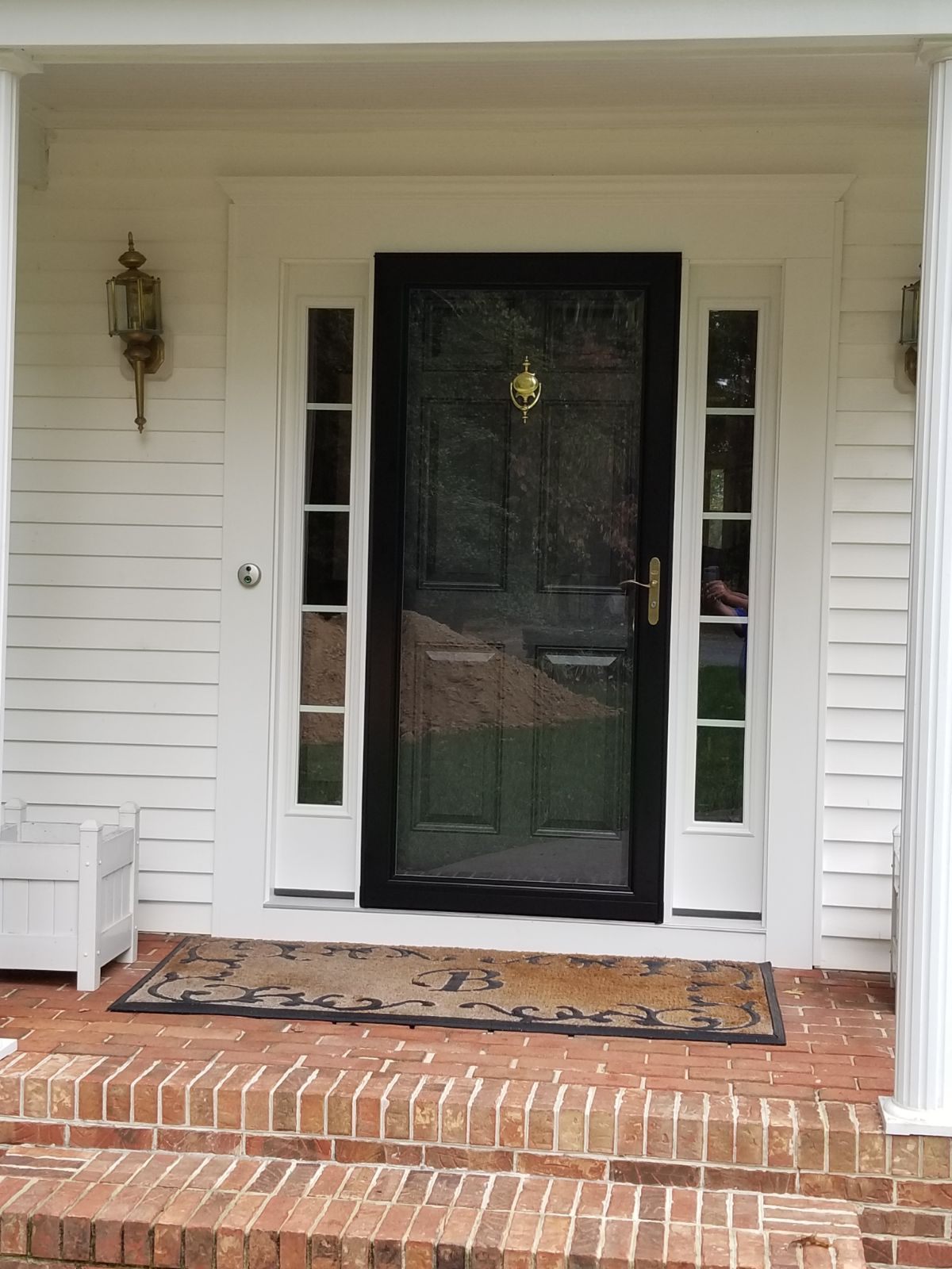 A white house with a black door and a brick porch