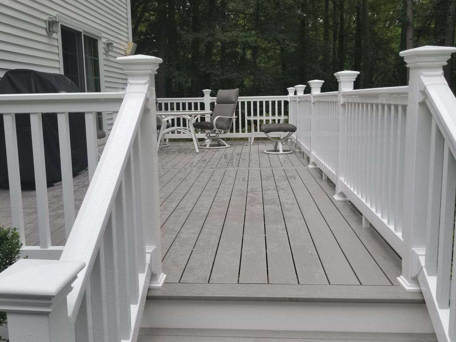 A deck with a white railing and chairs on it