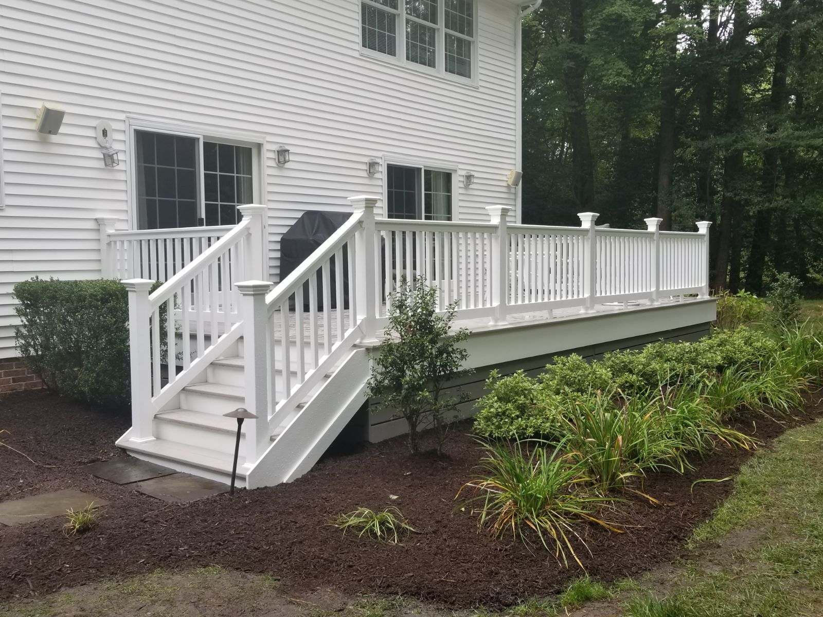 A white house with a white deck and stairs