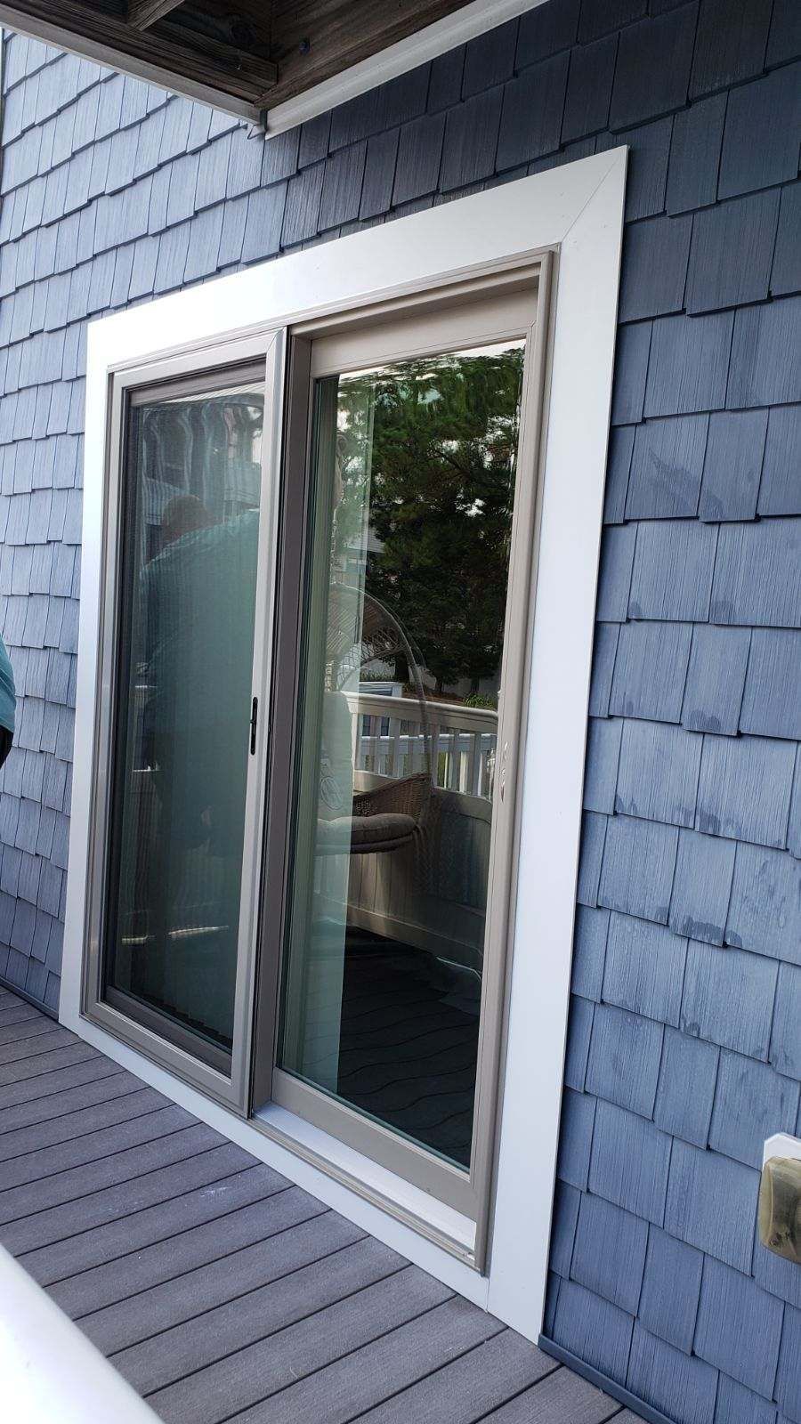 A sliding glass door is on the side of a blue house.