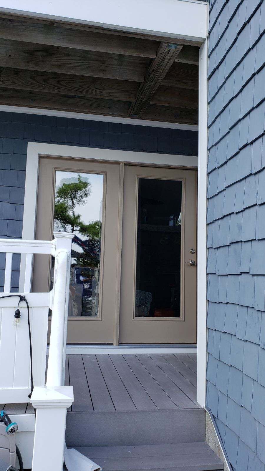 The front door of a house with a white railing and stairs leading up to it.