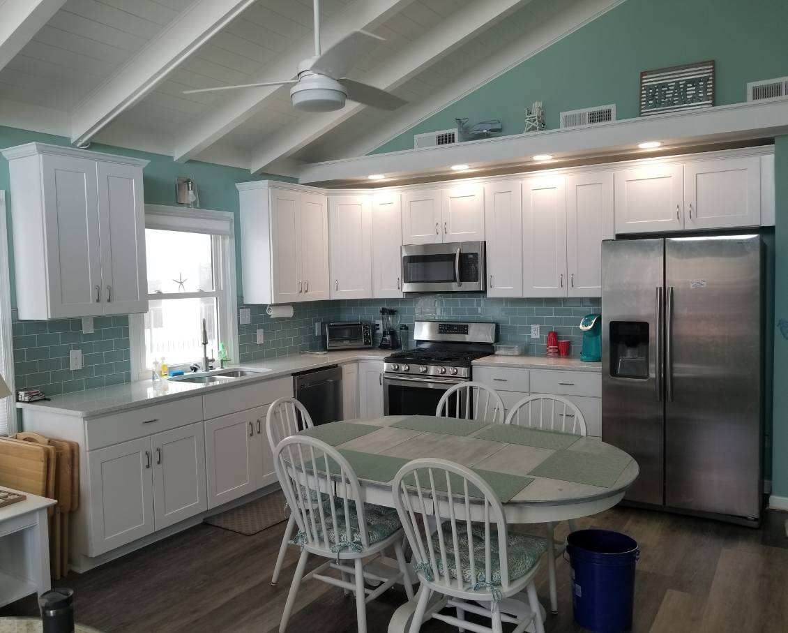 A kitchen with white cabinets, stainless steel appliances, a table and chairs.