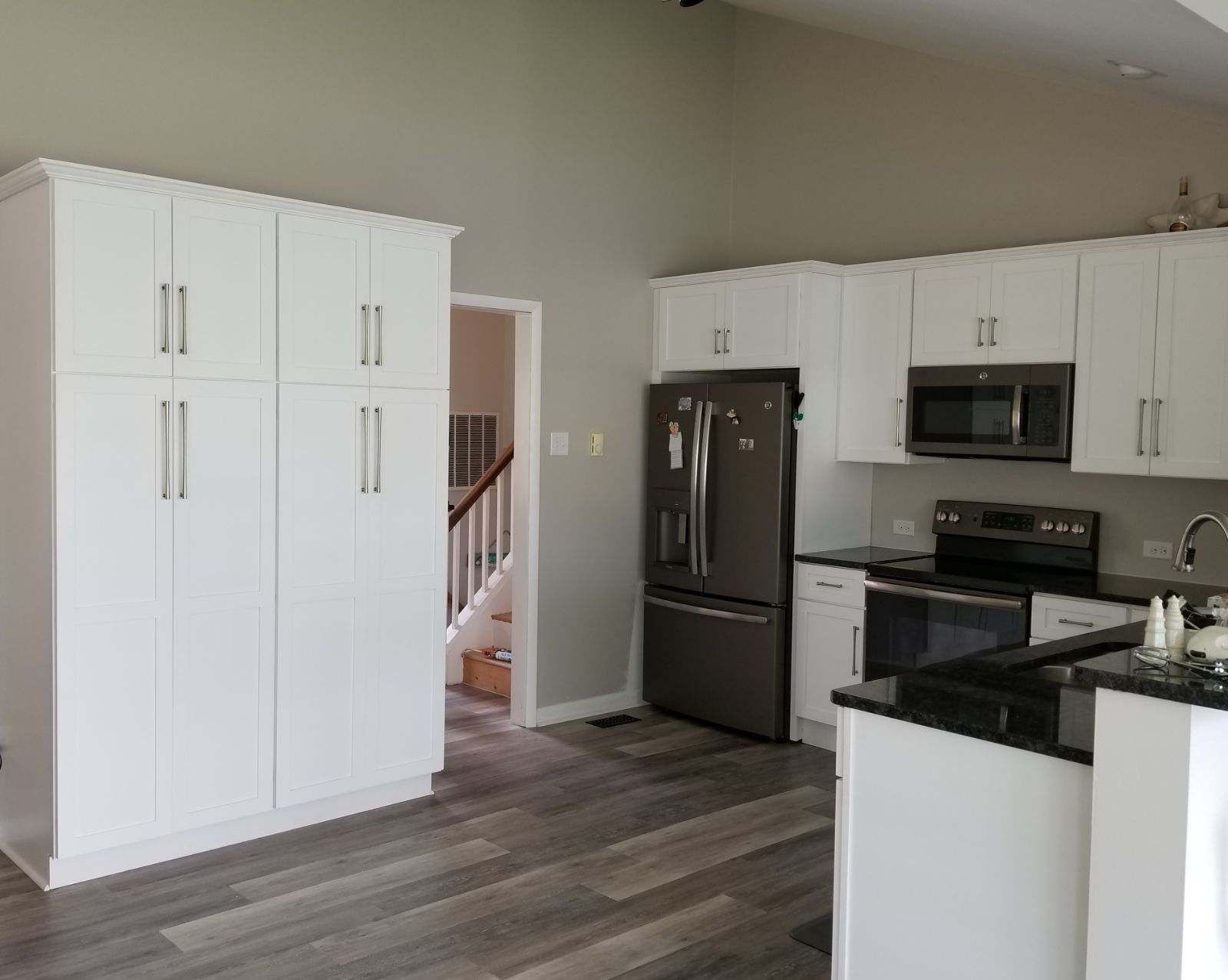 A kitchen with white cabinets, a refrigerator, stove, microwave and sink.