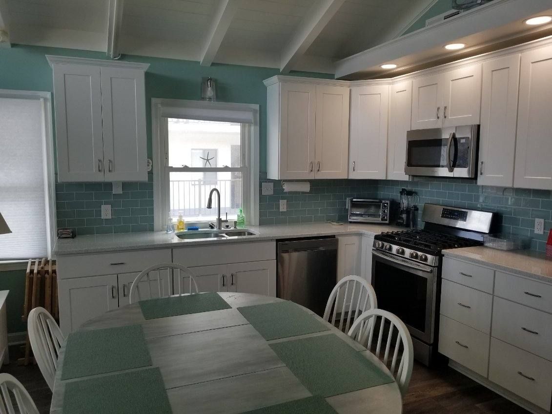 A kitchen with white cabinets, a stove, a sink, and a table.
