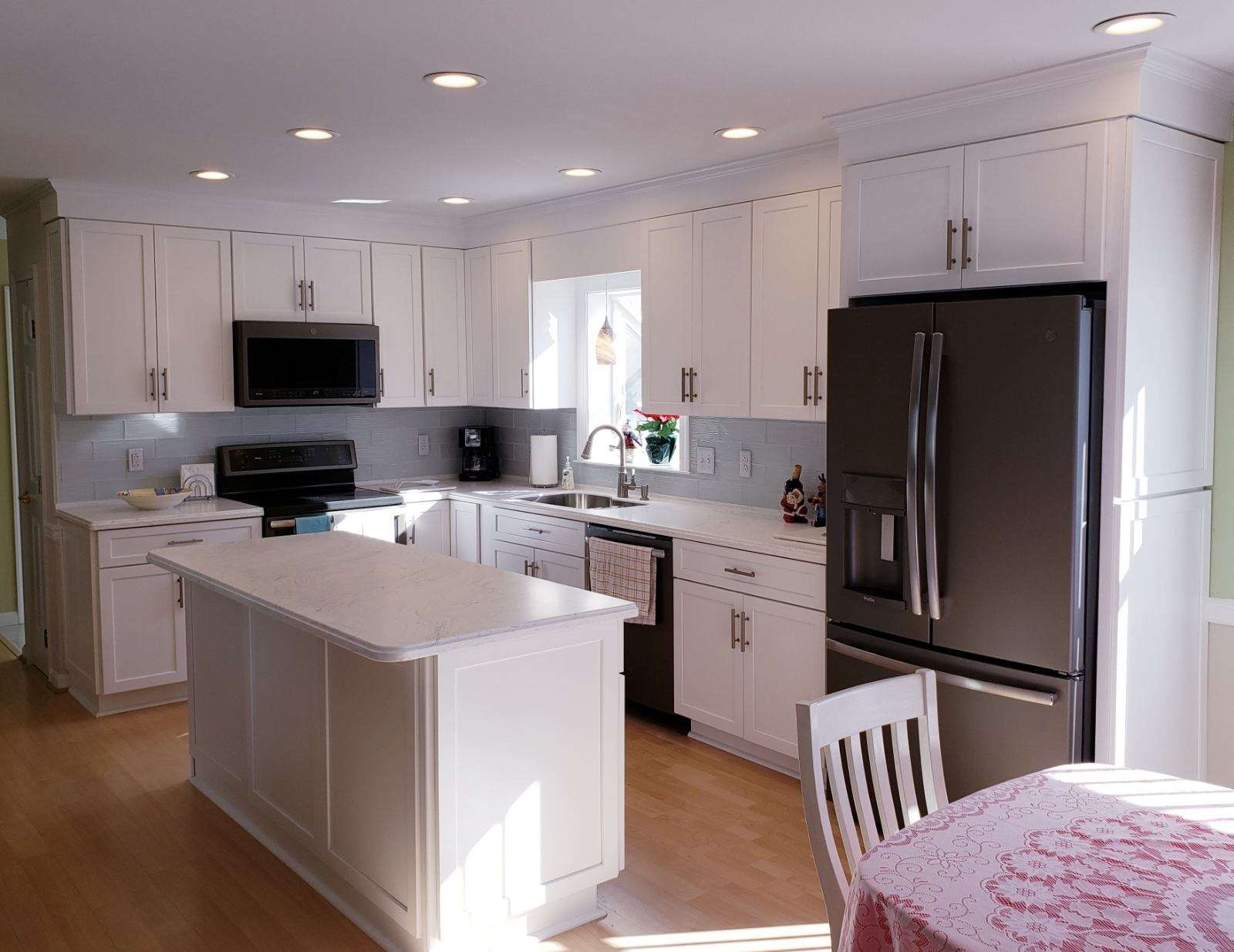 A kitchen with white cabinets and a stainless steel refrigerator