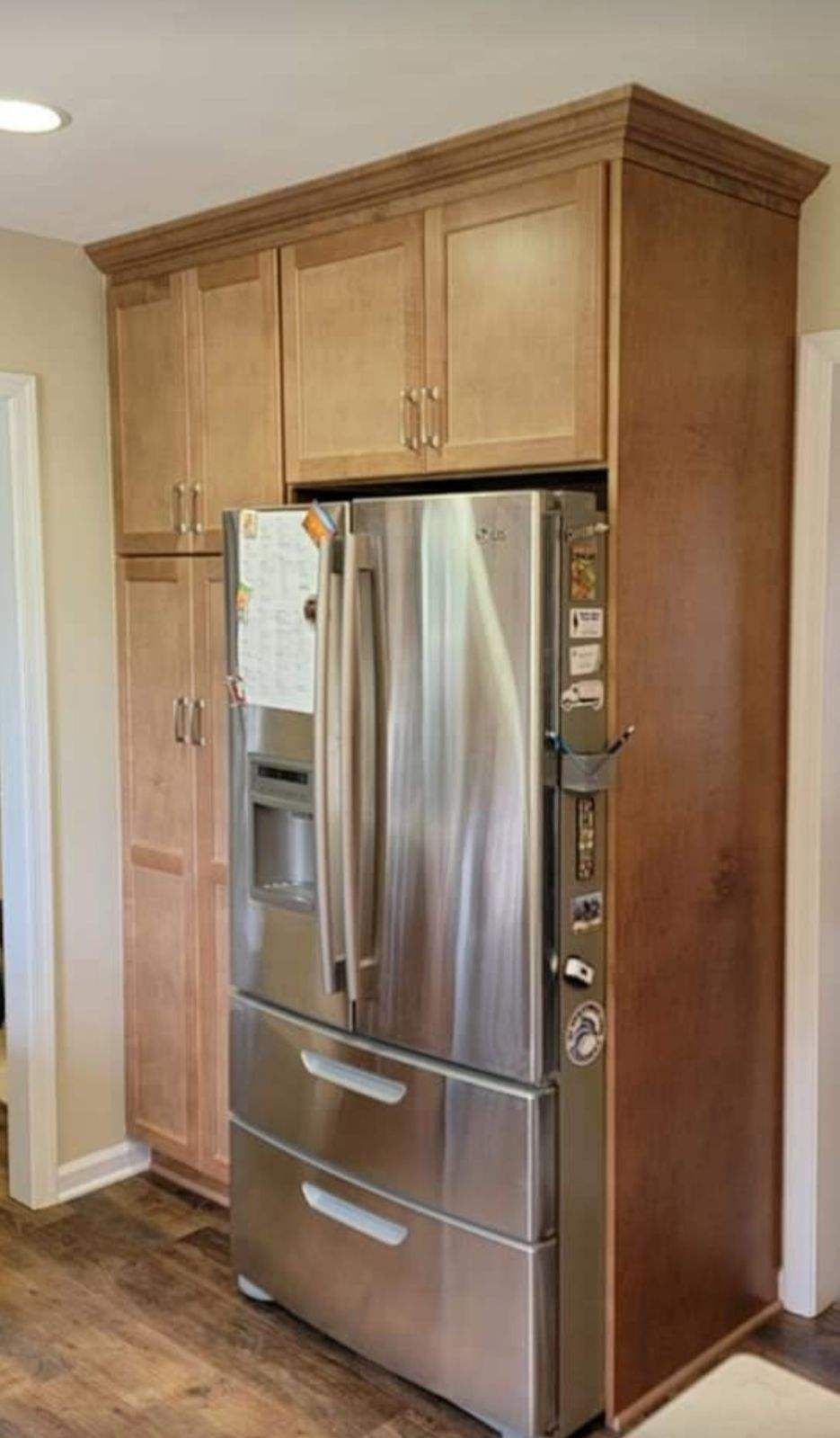 A stainless steel refrigerator is sitting in a kitchen with wooden cabinets.