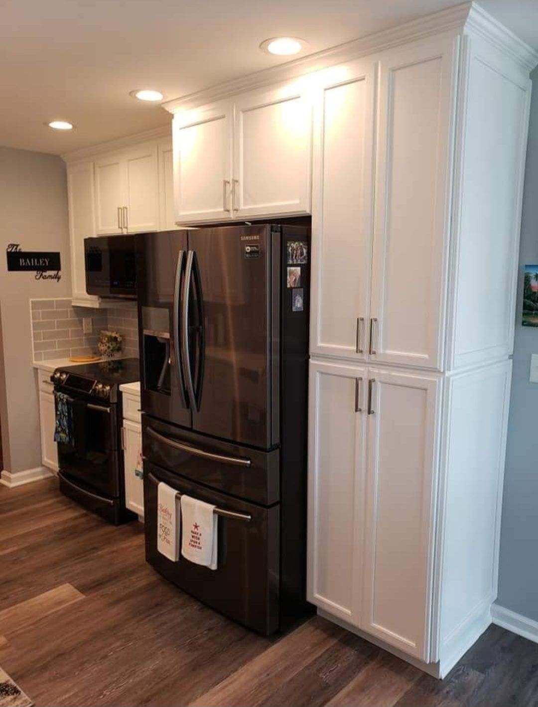 A kitchen with white cabinets and a black refrigerator.