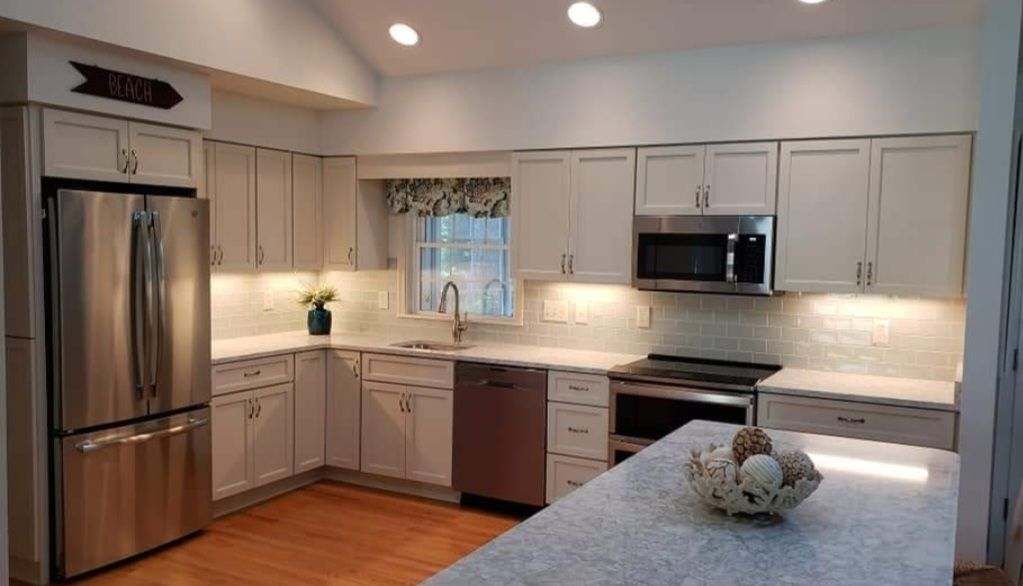 A kitchen with white cabinets, stainless steel appliances, and a large island.