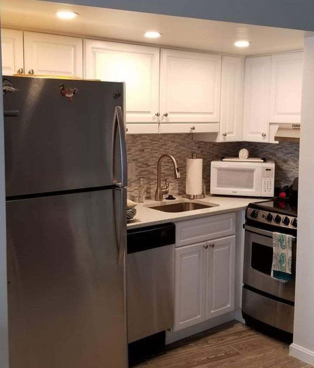 A kitchen with stainless steel appliances and white cabinets.