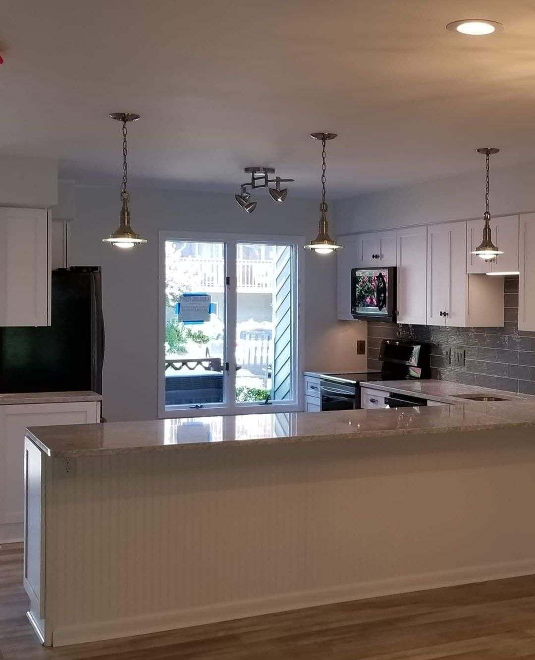 A kitchen with white cabinets and a large island in the middle