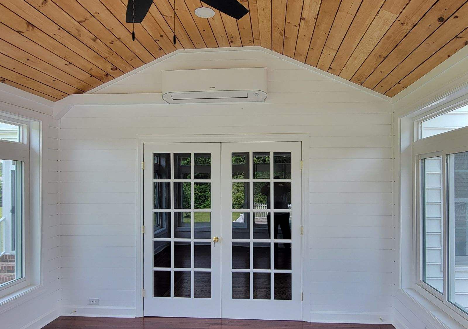 An empty room with a ceiling fan and french doors.
