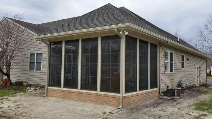 A screened in porch on the side of a house.