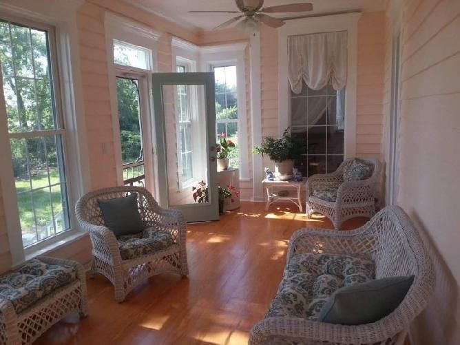 A sun room with wicker furniture and a ceiling fan