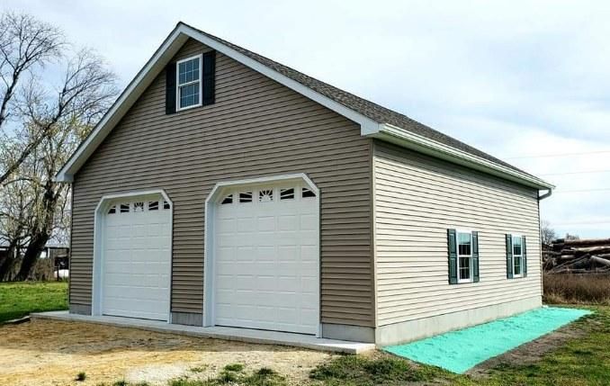 A garage with two white garage doors and two windows