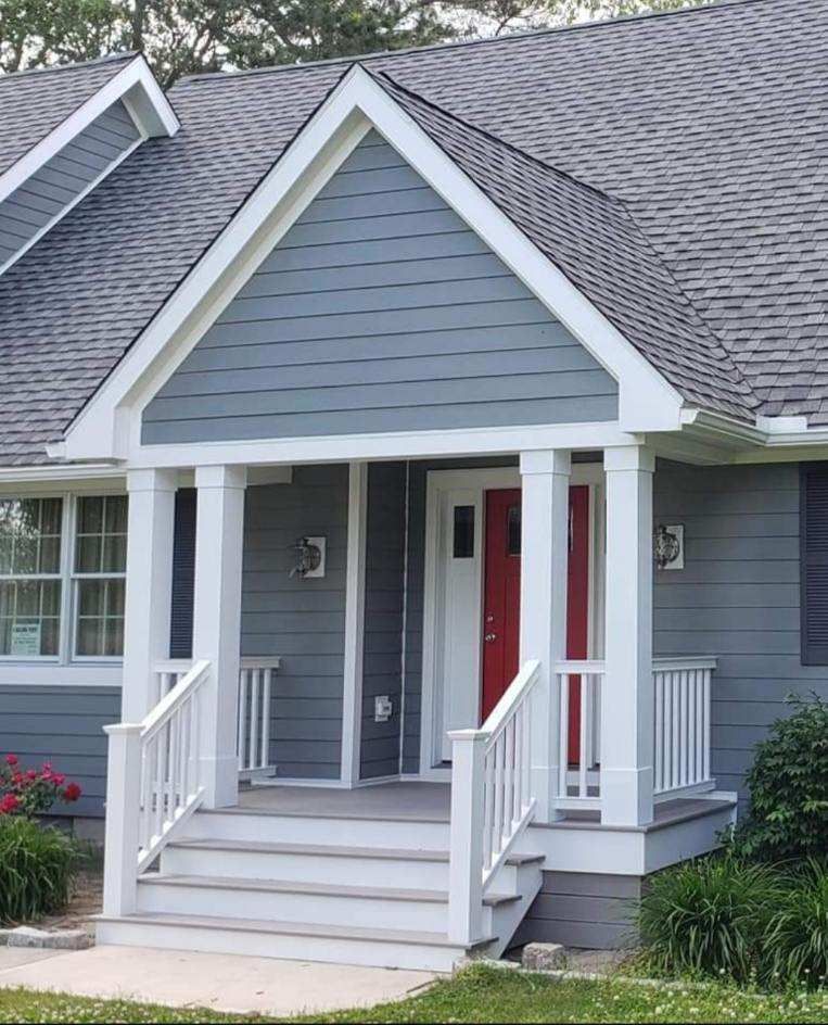 A blue house with a white porch and a red door
