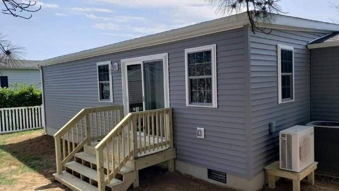 A small mobile home with a deck and stairs.