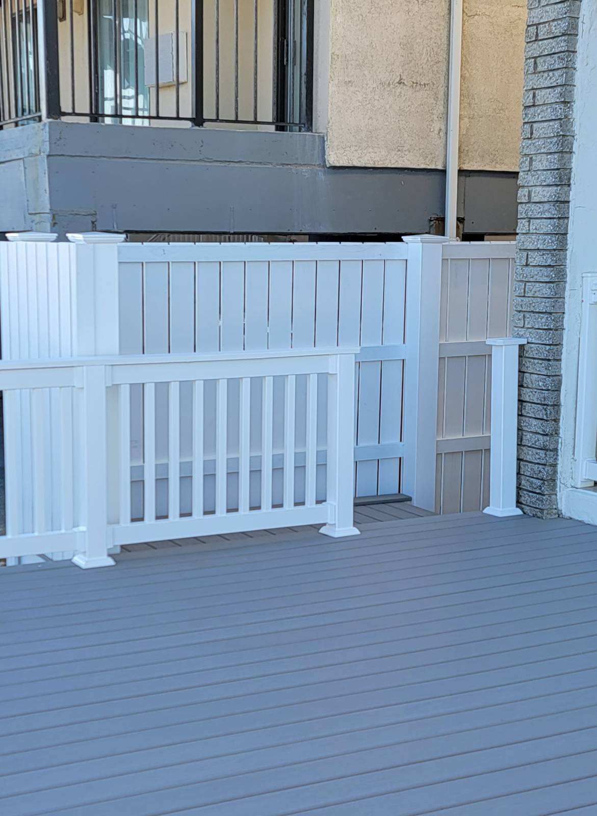 A white fence is sitting on top of a wooden deck.