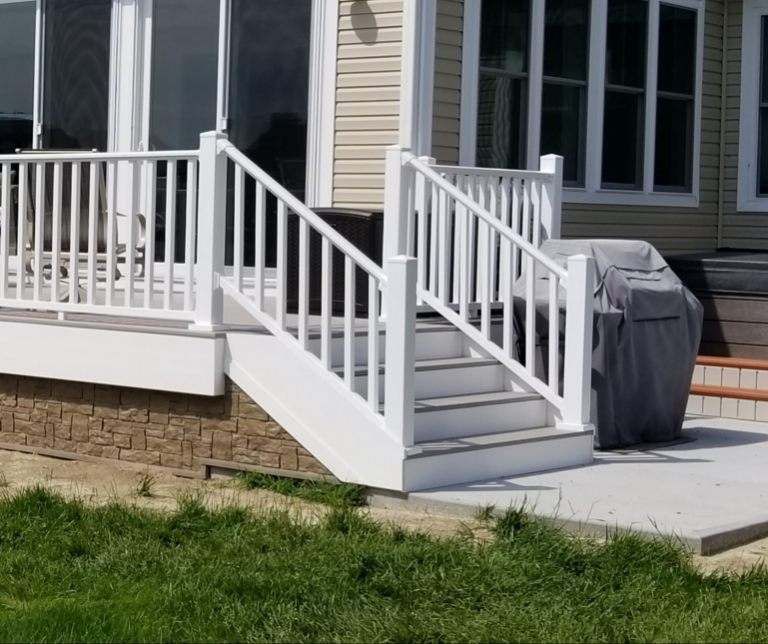 A white deck with stairs and a grill on it