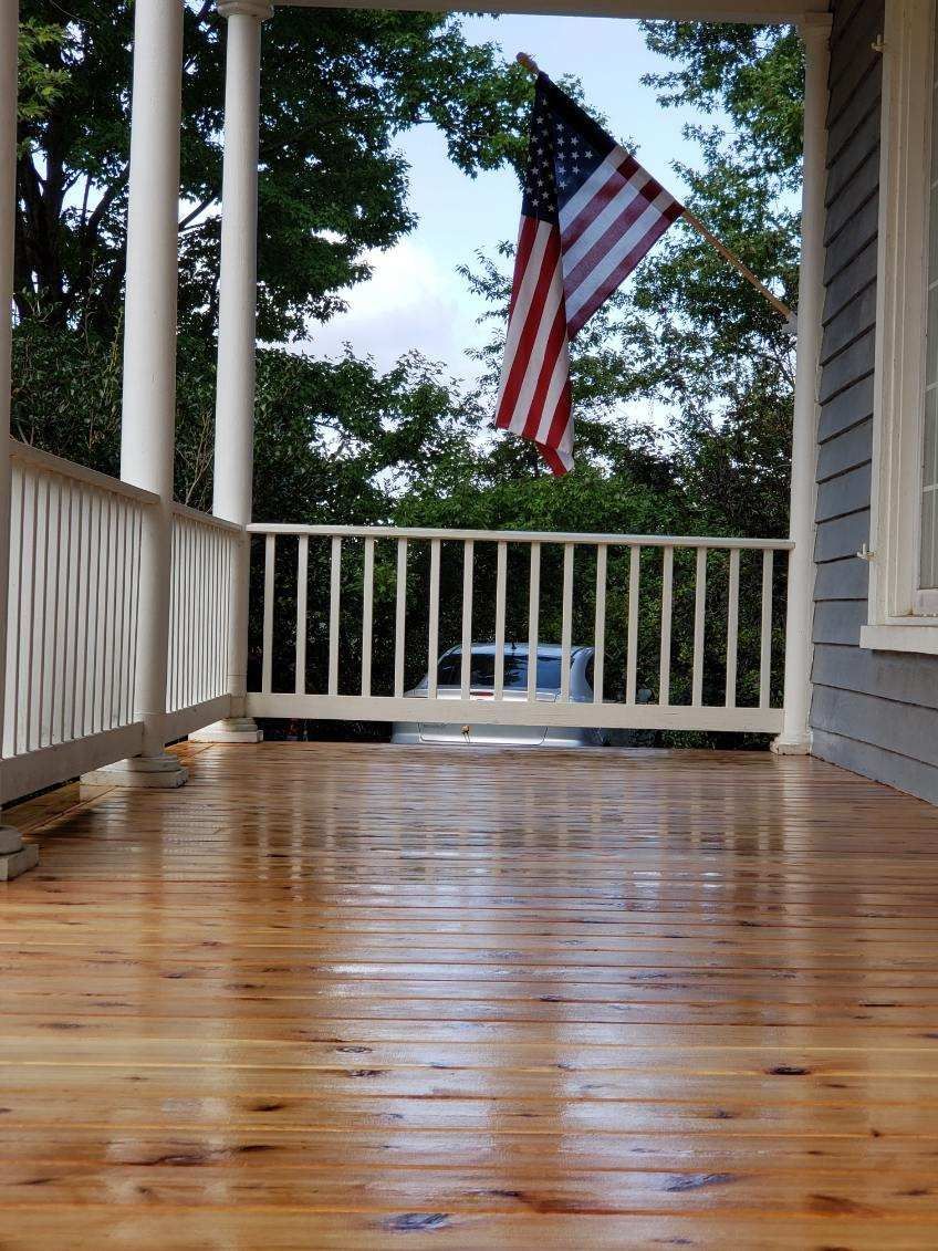 A porch with an American flag hanging from the railing