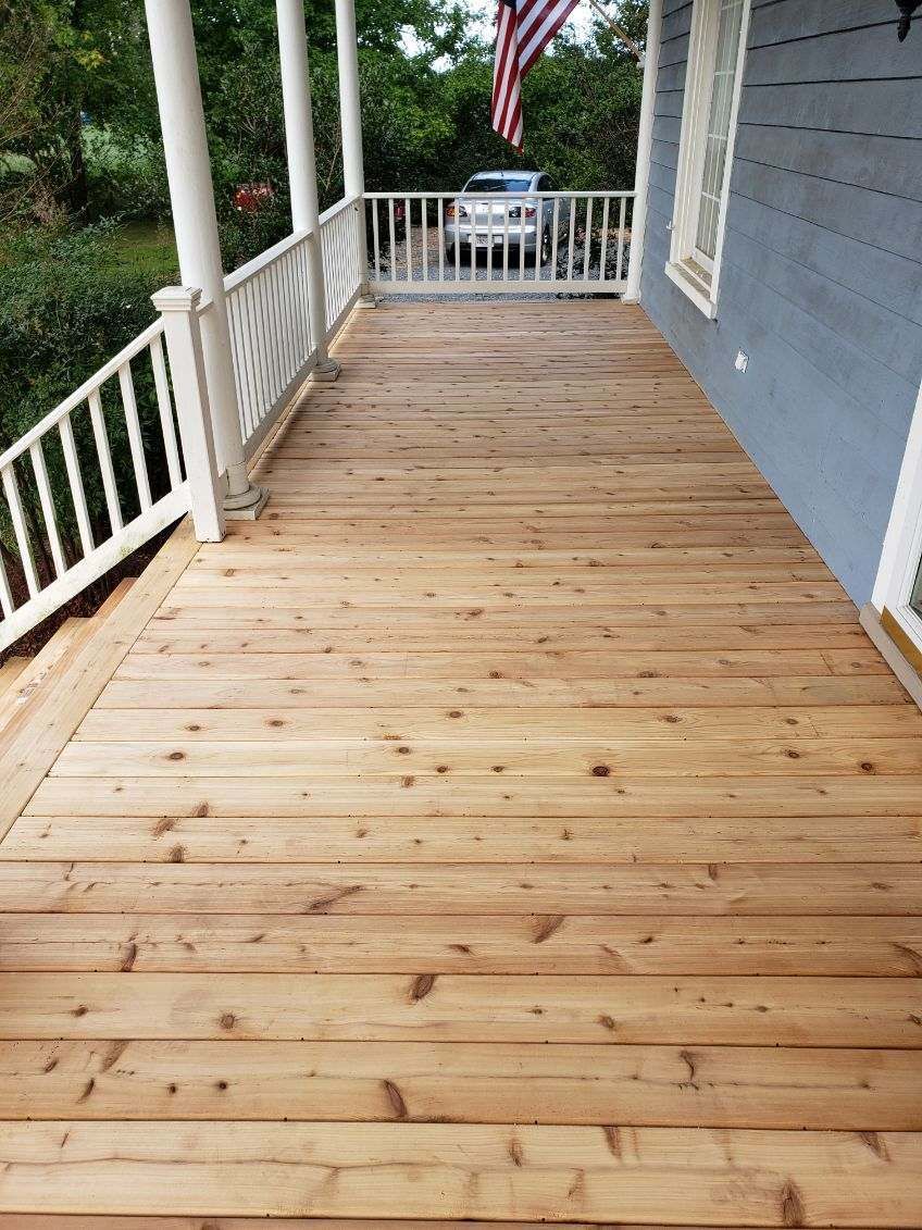 A wooden deck with a white railing and a car parked on it.