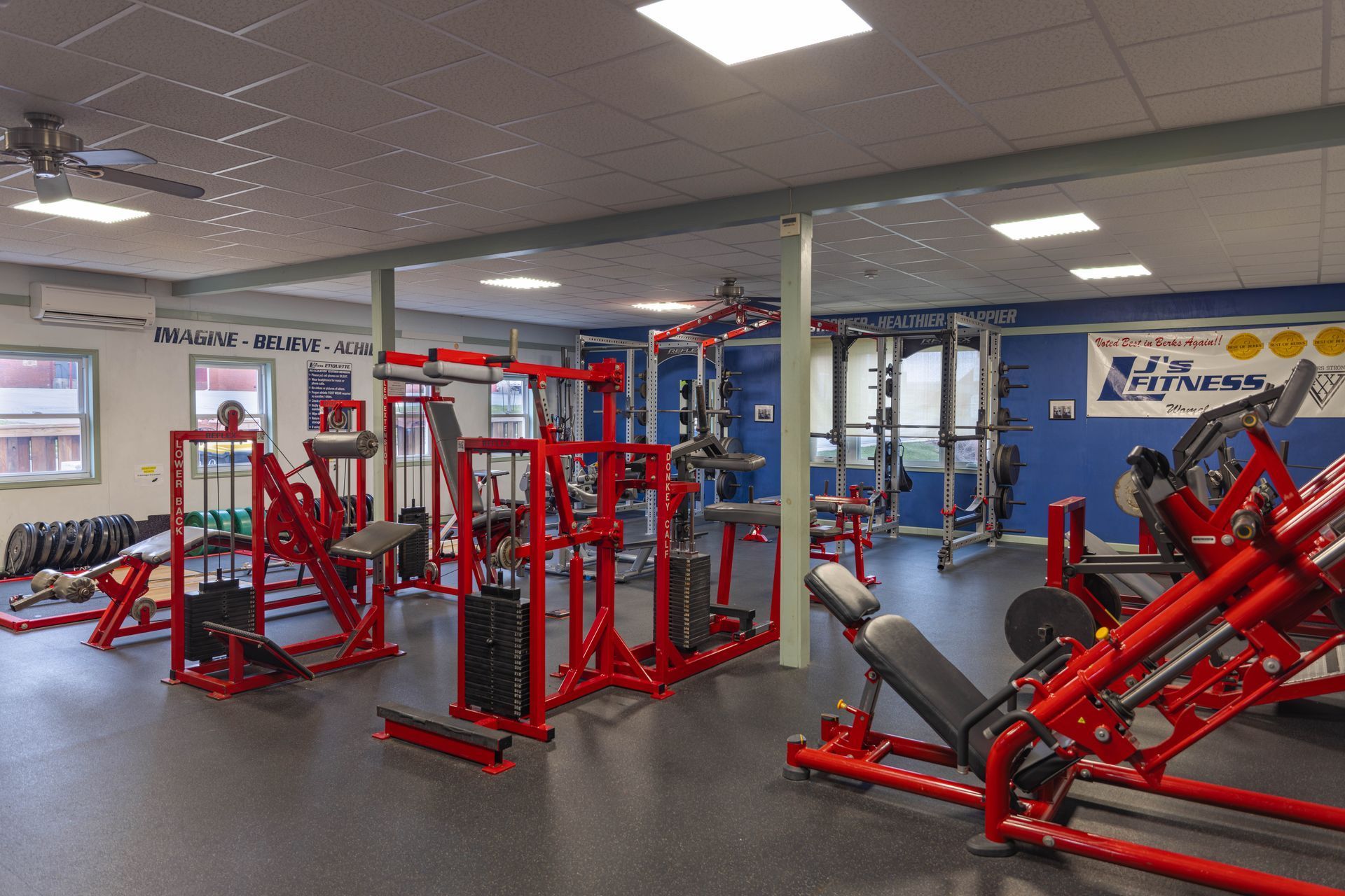 An indoor gym featuring various red-framed weight training and strength equipment on a gray floor.