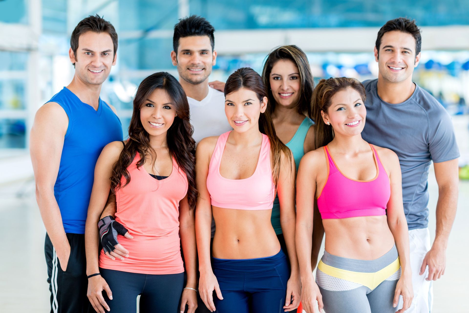Group of people in workout clothes smiling at the camera in a gym.